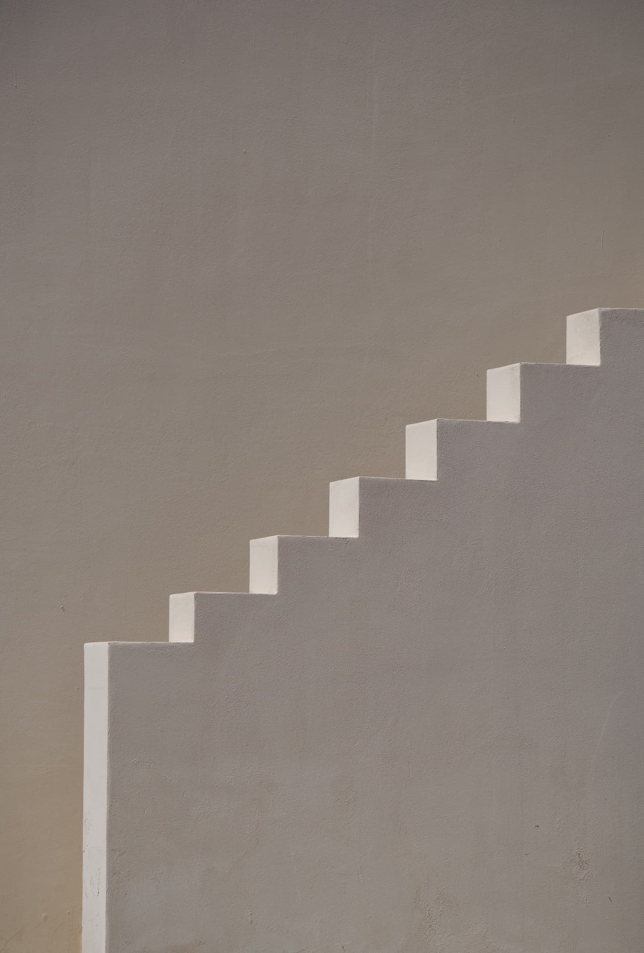 Minimal white stair profile against a warm plaster wall